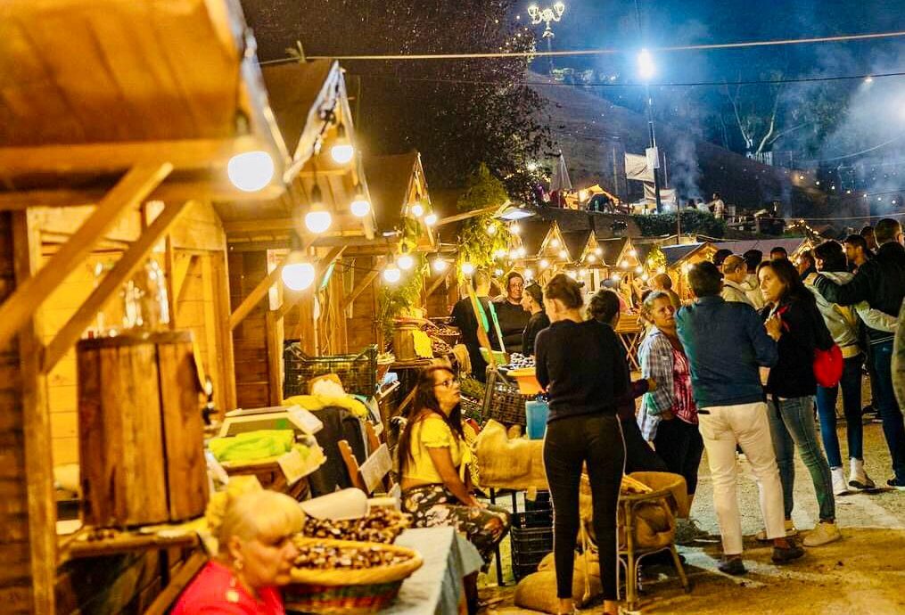 Le casette dei mercatini illuminate la sera, con i visitatori tra gli stand